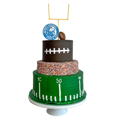 Three-tiered football-themed cake with decorative elements on a white background