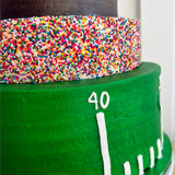 Green cake with a colorful sprinkled layer and number '40' on a white background