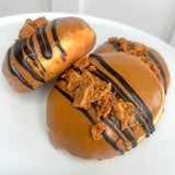 Three doughnuts with chocolate drizzle and crumb toppings on a white plate.