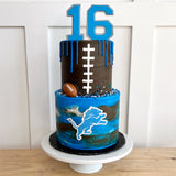 Two-tiered birthday cake with number 16, football design, and blue and brown color scheme on a white stand.