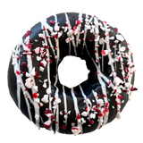 Decorative donut with chocolate glaze, white drizzle, and crushed peppermint on a white background