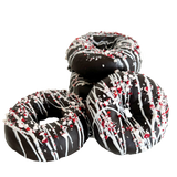 Decorative donut with chocolate glaze, white drizzle, and crushed peppermint on a white background