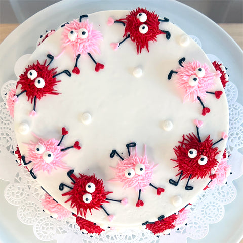 Decorative cake with red and pink characters on a white plate