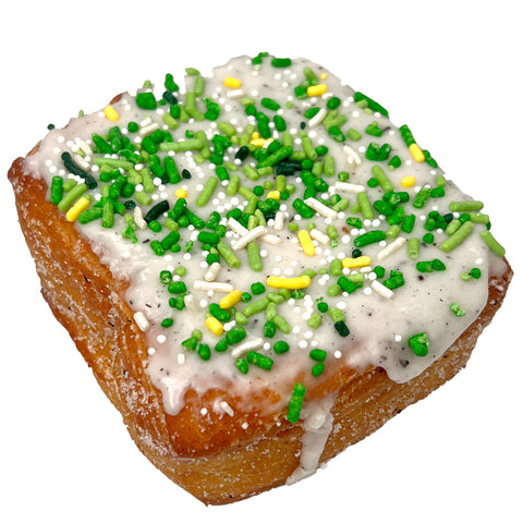 The Home Bakery Kronut with vanilla bean glaze and green and yellow sprinkles on a white background