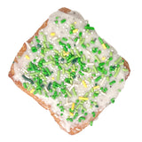 The Home Bakery Kronut with vanilla bean glaze and green and yellow sprinkles on a white background