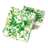 Rice Krispies Treats with white chocolate and green and yellow sprinkles on a white background